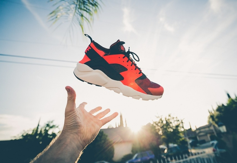 a hand throwing a trainer in the air